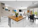 Open-concept kitchen with a large island featuring granite countertops, marble floors, and modern pendant lighting at 30 Via Vasari # 103, Henderson, NV 89011