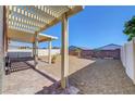 Backyard featuring a covered patio with a pergola, gravel landscaping, a small garden, and a white fence at 405 Prairie Moon Ave, North Las Vegas, NV 89084
