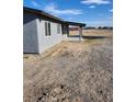 Exterior view of a home featuring gray siding, a covered porch, and a gravel yard at 4231 E Kellogg Rd, Pahrump, NV 89061