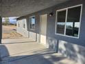 View of the covered patio featuring grey exterior walls, multiple windows and concrete flooring at 4231 E Kellogg Rd, Pahrump, NV 89061