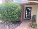 Cozy covered front porch with a chair, brick accents, decorative rocks, and a black front door at 5821 Santa Catalina Ave, Las Vegas, NV 89108