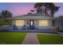 Charming single-story home with lush green lawn and inviting front porch at dusk at 615 D Ave, Boulder City, NV 89005