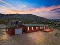 Exterior view of a red home with a detached garage and deck, set against a mountain landscape at 70 Camp Bonanza Rd, Las Vegas, NV 89124
