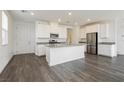 Bright, open kitchen featuring white cabinetry, gray countertops, and stainless steel appliances with gray wood flooring at 7777 Vino Vranec Ct, Las Vegas, NV 89113