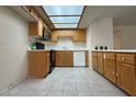 Functional kitchen with light wood cabinets, complete appliances, a bright skylight, and light tile flooring at 8410 Eldora Ave # 2046, Las Vegas, NV 89117