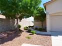 Landscaped front yard with green trees, small bushes, and decorative rock ground cover at 9705 Templemore Ave # 102, Las Vegas, NV 89129