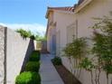 A narrow side yard with green shrubs and bushes along a concrete block wall at 9705 Templemore Ave # 102, Las Vegas, NV 89129