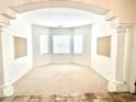 Bright and airy living room with neutral carpeting, large windows, and decorative pillars at 10816 Elm Ridge Ave, Las Vegas, NV 89144