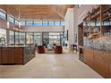 Open-concept great room with wood ceilings, stone fireplace, a bar, and floor to ceiling windows showcasing backyard views at 11707 Discovery Canyon Dr, Las Vegas, NV 89135