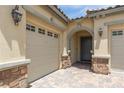 Close up view of a stucco home with an arched entryway framed by stone pillars and a paver driveway at 3084 Porte La Paz Ave, Henderson, NV 89044