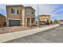 Two-story tan home with a two car garage and brick paver driveway leading up to the garage at 6207 Hamilton Ave, Las Vegas, NV 89122