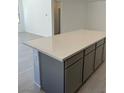 Close-up of kitchen island, displaying gray cabinetry and an impressive quartz countertop at 66 Via Montoro, Henderson, NV 89015