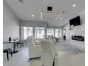 Bright living room featuring white leather seating, a modern fireplace, and expansive windows overlooking the backyard at 8150 Beaverbrook Way, Las Vegas, NV 89123