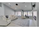 A bright, open living area with white leather sofas, large windows, and modern lighting fixture at 8150 Beaverbrook Way, Las Vegas, NV 89123