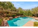 Backyard pool with spa, rock wall, and lush landscaping on a sunny day at 900 Cantura Mills Rd, Henderson, NV 89052