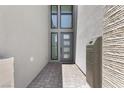 The covered entryway featuring textured walls, modern windows, and an elegant front door at 10927 White Clay Dr, Las Vegas, NV 89135