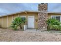 Close up of a single story home with a stone chimney and desert landscaping at 1607 Vegas Valley Dr, Las Vegas, NV 89169