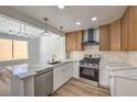 Bright kitchen with a gas range, stainless steel appliances, light wood cabinets and a marble countertop island at 2117 Desert Peak Rd, Las Vegas, NV 89134