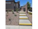 Landscaped walkway featuring gravel groundcover and gray steps with yellow trim to a gated entry at 289 Aravalli Crest St, Henderson, NV 89015