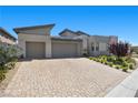 Stunning single-story home with a three-car garage and elegant stone driveway on a bright, sunny day at 5166 Stone View Dr, Las Vegas, NV 89135