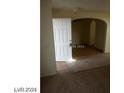 Entryway with white door, tan carpet, and tile with an arched doorway leading to another room at 5308 La Quinta Hills St, North Las Vegas, NV 89081