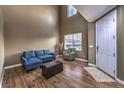 Bright living room features high ceilings, wood floors, and a comfortable blue sectional at 5480 Oatfield St, North Las Vegas, NV 89081