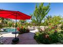 Tranquil backyard with a sparkling pool, waterfall, and red umbrella at 8221 Bay Dunes St, Las Vegas, NV 89131