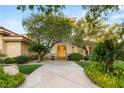 Inviting home exterior featuring mature trees, a stone walkway, and a beautiful wooden front door at 1383 Opal Valley St, Henderson, NV 89052