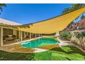 Backyard with covered outdoor seating, a pool, lush landscaping, and shade sail at 1905 Dakota Hills Ave, Las Vegas, NV 89123
