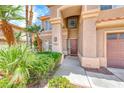 Close-up of home's entry featuring an arched doorway with decorative pillars, complemented by well-kept greenery and desert landscaping at 2741 Chokecherry Ave, Henderson, NV 89074
