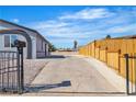 Large driveway and wooden fence lead to a backyard with desert landscaping at 5580 Waltham Ln, Las Vegas, NV 89122