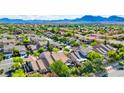 A scenic view of a suburban neighborhood featuring lush landscaping and mountain views at 602 Painted Cloud Pl, Las Vegas, NV 89144