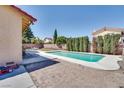 Backyard featuring a sparkling pool with lounge chairs on the patio, surrounded by lush greenery and a block fence at 864 E Eldorado Ln, Las Vegas, NV 89123