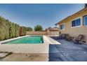 Backyard featuring a sparkling pool with lounge chairs on the patio, surrounded by lush greenery and a block fence at 864 E Eldorado Ln, Las Vegas, NV 89123