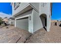 Angle view of a gray home showing the two-car garage, paver driveway and an arched entryway at 8786 Sand Verbena Ave, Las Vegas, NV 89117
