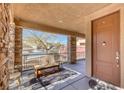 Inviting front porch featuring stone columns, a seating area, and a welcoming entryway at 10212 Cider Mill Rd, Las Vegas, NV 89135