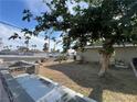 Wide shot of the home's backyard with a large tree and ample space for customization at 1429 S Sandhill Rd, Las Vegas, NV 89104
