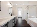 Bright bathroom featuring double vanity, soaking tub, and a glass-enclosed shower at 1601 Iguana St, Pahrump, NV 89048