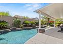 Tranquil backyard oasis with a freeform pool, lush landscaping, covered patio, and ample seating at 2025 Dakota Lodge Ave, Las Vegas, NV 89123