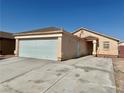 Exterior view of a tan single-story home with a large garage and desert landscaping at 2621 Blue Reef Dr, North Las Vegas, NV 89032