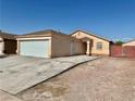 Exterior view of a tan single-story home with a large garage and desert landscaping at 2621 Blue Reef Dr, North Las Vegas, NV 89032
