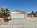 Exterior view of a tan single-story home with a large garage and desert landscaping at 2621 Blue Reef Dr, North Las Vegas, NV 89032