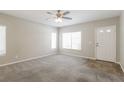 Bright living room with a large window, neutral carpet, a ceiling fan, and a white front door at 3209 Cheltenham St, Las Vegas, NV 89129