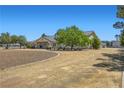 Expansive front yard with a circular driveway leading to a well-maintained home with mature trees and landscaping at 3231 Rebel Ave, Pahrump, NV 89048
