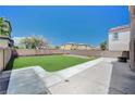 Spacious backyard area with artificial turf, concrete patio and block wall fencing at 412 Orchid Oasis Ave, North Las Vegas, NV 89031