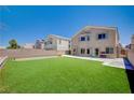 Expansive backyard featuring a lush lawn, block wall fencing, and patio area at 412 Orchid Oasis Ave, North Las Vegas, NV 89031