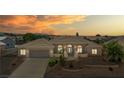 Dusk view of one-story home featuring tile roof, arched entry, desert landscaping, and two-car garage at 6841 Longmeadow Dr, Pahrump, NV 89061