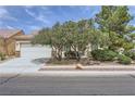 Well-manicured front yard with mature trees and shrubs complementing the home's exterior at 7465 Widewing Dr, North Las Vegas, NV 89084