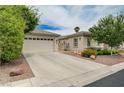 View of single story home featuring desert landscaping, a large driveway, and a two-car garage at 7606 Grove Acre Ct, Las Vegas, NV 89131