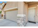 Close-up of the entry door and garage of a stucco home with stone accents at 7963 Cape Brett St, Las Vegas, NV 89131